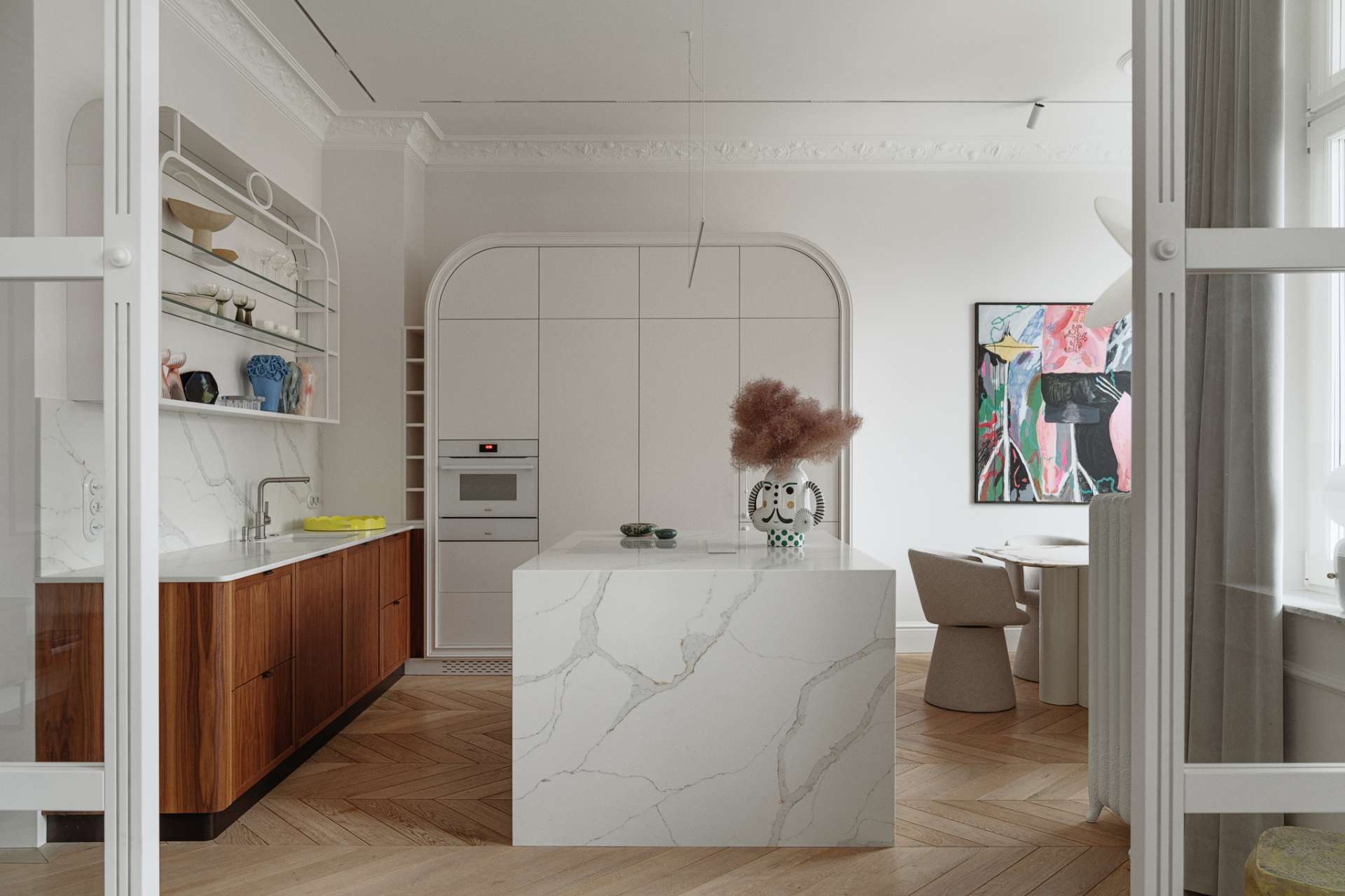 This kitchen pairs sculptural softness with practical sophistication. A central island in marble-look stone anchors the space, its clean lines echoed in the curved cabinetry and arched built-ins. Walnut lower cabinets add warmth and grain, while open shelving displays a curated mix of ceramics and glassware. 
